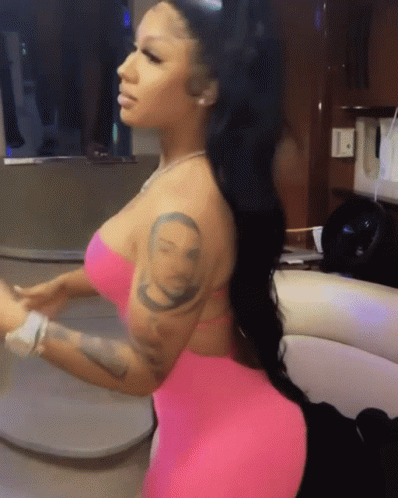 A Woman In A Pink Dress Has A Tattoo On Her Arm Of A Man 'S Face GIF