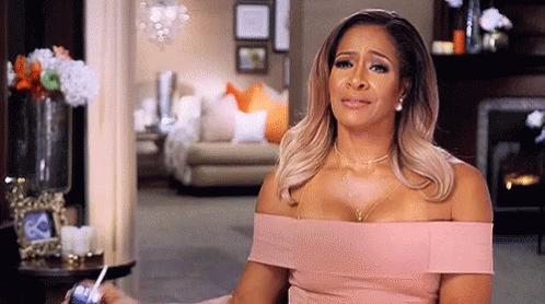 A Woman In A Pink Dress Is Crying In A Living Room . GIF