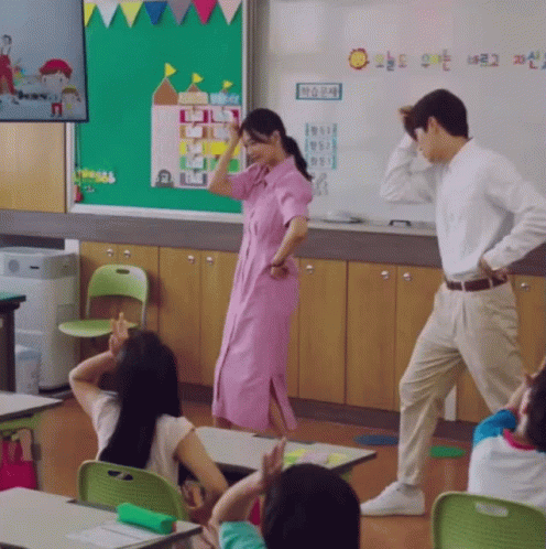 A Woman In A Pink Dress Is Dancing In A Classroom With A Sign That Says " Sun " On It GIF