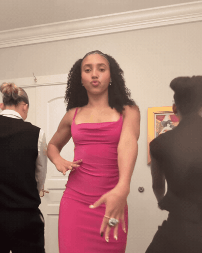 A Woman In A Pink Dress Is Dancing In Front Of A Door GIF