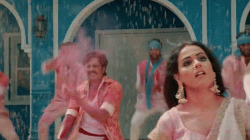 A Woman In A Pink Dress Is Dancing With A Group Of Men GIF