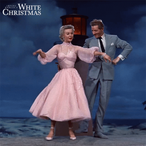 A Woman In A Pink Dress Is Dancing With A Man In A Suit In A White Christmas Poster GIF
