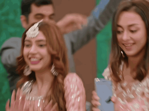 A Woman In A Pink Dress Is Holding A Blue Iphone GIF
