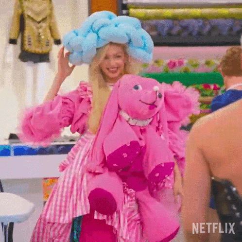 A Woman In A Pink Dress Is Holding A Stuffed Elephant GIF