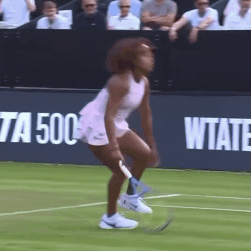 A Woman In A Pink Dress Is Holding A Tennis Racquet On A Tennis Court In Front Of A Sign That Says Wtate GIF