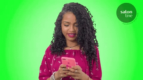 A Woman In A Pink Dress Is Looking At Her Cell Phone GIF