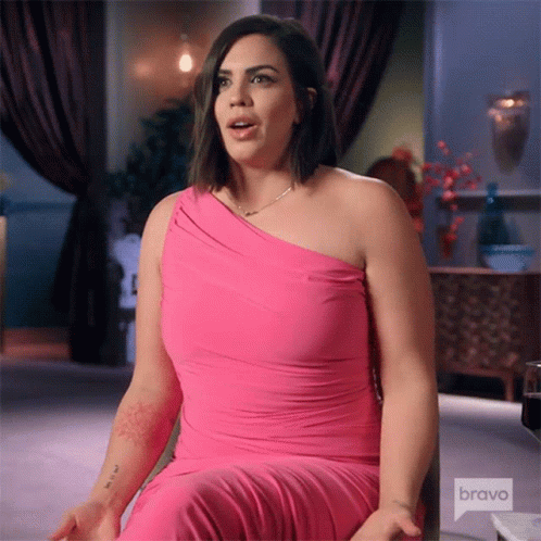 A Woman In A Pink Dress Is Sitting In A Chair On Bravo Television . GIF