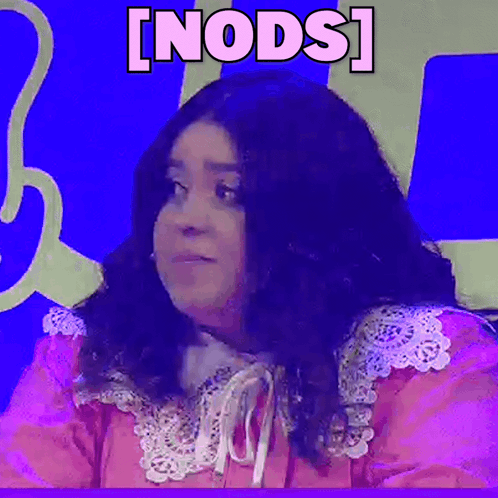A Woman In A Pink Dress Is Sitting In Front Of A Blue Wall With The Word Nods Written On It . GIF