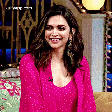 A Woman In A Pink Dress Is Smiling While Sitting On A Couch In A Room . GIF
