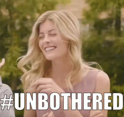A Woman In A Pink Dress Is Smiling With The Words # Unbothered Written Above Her . GIF