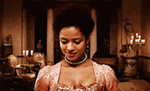 A Woman In A Pink Dress Is Standing In A Room With Candles On The Walls GIF