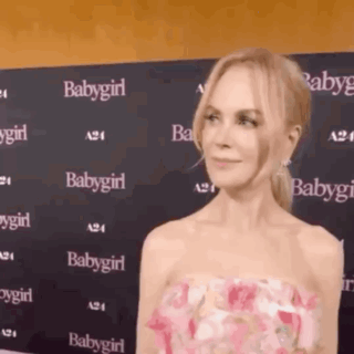 A Woman In A Pink Dress Is Standing In Front Of A Wall That Says Babygirl On It . GIF