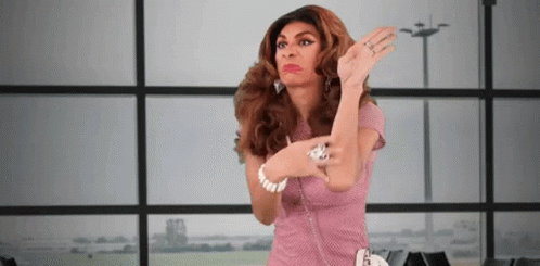 A Woman In A Pink Dress Is Standing In Front Of A Window With Her Hands In The Air . GIF