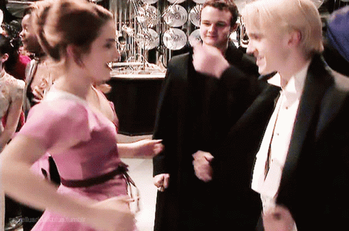 A Woman In A Pink Dress Is Standing Next To A Man In A Tuxedo GIF