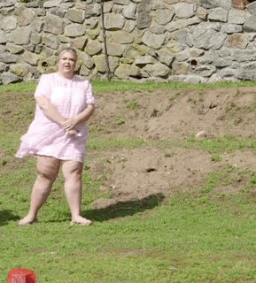 A Woman In A Pink Dress Is Standing On A Grassy Hill . GIF