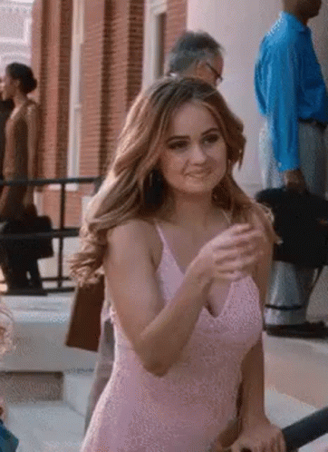 A Woman In A Pink Dress Is Standing On The Steps Of A Building . GIF