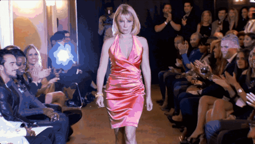 A Woman In A Pink Dress Is Walking Down The Runway GIF