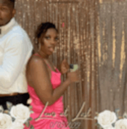 A Woman In A Pink Dress Stands Next To A Man In A White Shirt . GIF