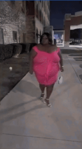 A Woman In A Pink Dress Stands On A Sidewalk GIF
