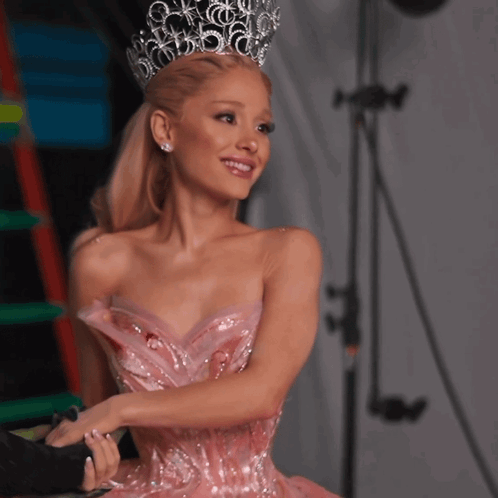 A Woman In A Pink Dress With A Crown On Her Head Is Smiling GIF
