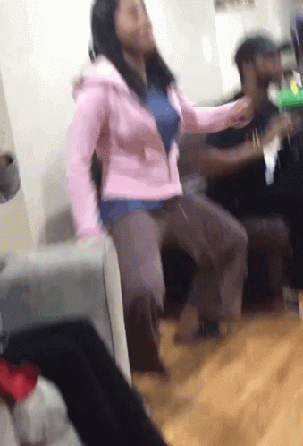 A Woman In A Pink Jacket Is Dancing In A Room With Other People GIF