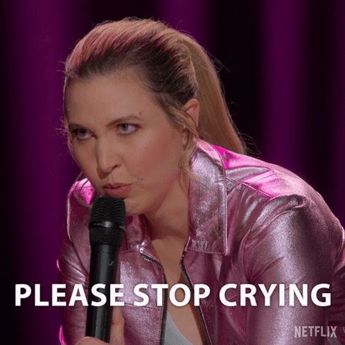 A Woman In A Pink Jacket Is Holding A Microphone With The Words Please Stop Crying Below Her GIF