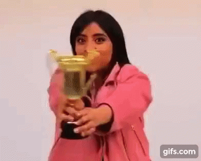 A Woman In A Pink Jacket Is Holding A Trophy . GIF