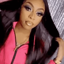 A Woman In A Pink Jacket Is Holding Her Hair In Her Hand . GIF
