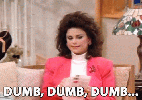 A Woman In A Pink Jacket Is Sitting On A Couch And Says Dumb Dumb Dumb .. GIF