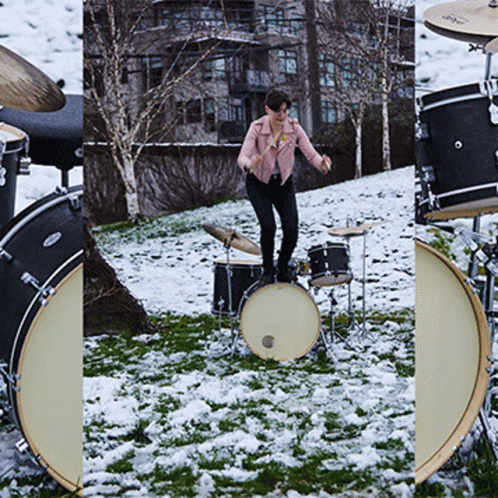 A Woman In A Pink Jacket Is Standing On A Drum Set In The Snow GIF