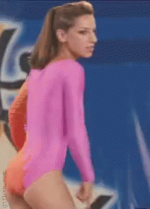 A Woman In A Pink Leotard Stands In Front Of A Blue Background GIF