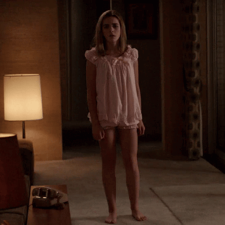 A Woman In A Pink Nightgown Stands In A Dark Room GIF