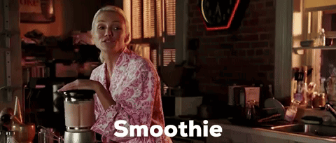A Woman In A Pink Robe Is Making A Smoothie GIF