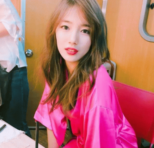 A Woman In A Pink Robe Sits In A Chair GIF