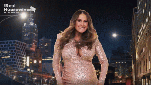 A Woman In A Pink Sequined Dress Is Standing In Front Of A Real Housewives Logo GIF