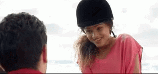 A Woman In A Pink Shirt And A Black Helmet Is Smiling At A Man . GIF