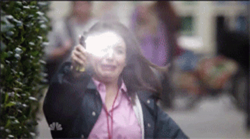 A Woman In A Pink Shirt And A Blue Jacket Is Holding A Flashlight GIF