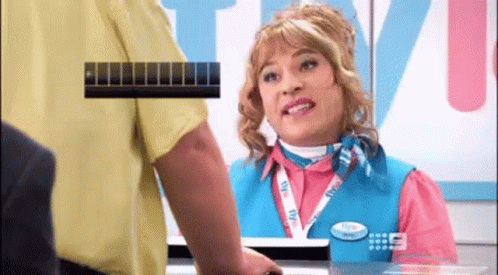 A Woman In A Pink Shirt And Blue Vest Is Talking To A Man GIF