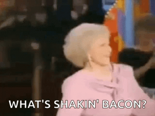 A Woman In A Pink Shirt Is Dancing And Saying What 'S Shakin ' Bacon . GIF