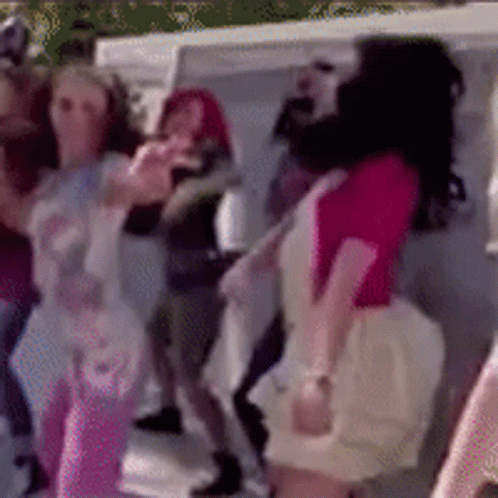 A Woman In A Pink Shirt Is Dancing In A Crowd Of People GIF