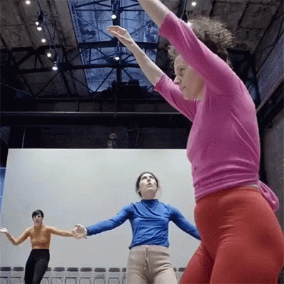 A Woman In A Pink Shirt Is Dancing With Another Woman GIF