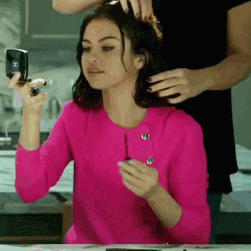 A Woman In A Pink Shirt Is Getting Her Hair Done By Another Woman GIF