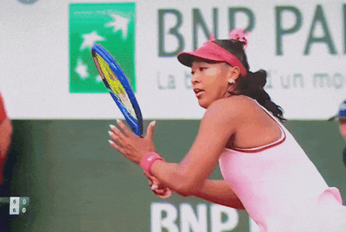 A Woman In A Pink Shirt Is Holding A Tennis Racquet In Front Of A Bnp Pa Sign GIF