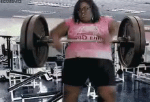 A Woman In A Pink Shirt Is Lifting A Barbell In A Gym GIF