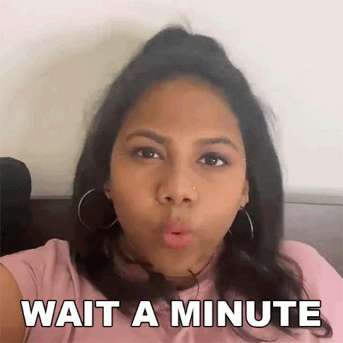 A Woman In A Pink Shirt Is Making A Funny Face And Says Wait A Minute GIF