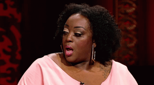 A Woman In A Pink Shirt Is Making A Funny Face With Her Mouth Open GIF