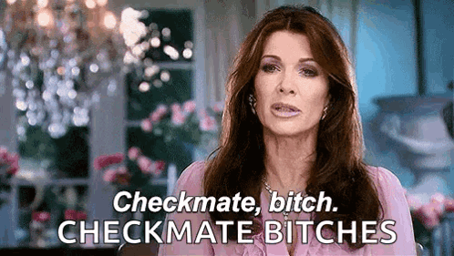 A Woman In A Pink Shirt Is Saying Checkmate Bitch Checkmate Bitches In Front Of A Chandelier . GIF