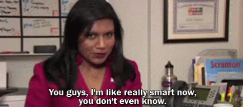 A Woman In A Pink Shirt Is Sitting At A Desk Talking On A Telephone . GIF
