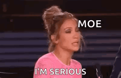 A Woman In A Pink Shirt Is Sitting In Front Of A Microphone And Making A Funny Face . GIF