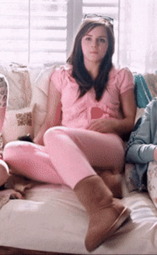 A Woman In A Pink Shirt Sits On A Couch GIF